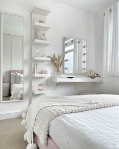 a white bed sitting under a mirror in a bedroom