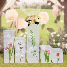 three vases with flowers on them sitting in the grass