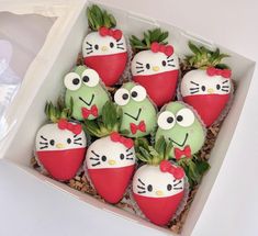 hello kitty strawberries are in a box with green and red frosting on them