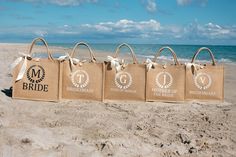 three brown bags with white ribbons tied to them on the sand at the beach near the ocean