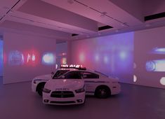 two police cars parked next to each other in a room with large screens on the wall