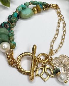 This stunning bracelet is made with beautiful high quality Turquoise Nugget Beads, Gold filled Cable Chain and more!  The asymmetrical design is so pretty with the Toggle Clasp hammered for texture and style The other beads are Heishi Aventurine, Pearls, Czech Hibiscus, Spacer Beads, & Glass Czech Beads  The Gold Alloy Butterfly Charm is lightweight and next to the Gold Plated Lotus Charm they are the perfect touch to finish off this amazing bracelet.  This bracelet is 7 inches big fits asymmetrically with the toggle in the side of the wrist. It is comfortable and would look great as an addition to your bracelet collection! It is not adjustable.  I appreciate your business and do my little happy dance with every sale!  I hope you can see my real passion and attention I give to making each Bohemian Gold Pearl Bracelet With Gemstone Beads, Gold Bohemian Pearl Bracelet With Gemstone Beads, Turquoise Metal Beaded Bracelets For Jewelry Making, Green Bohemian Metal Beaded Bracelets, Green Bohemian Metal Beaded Bracelet, Handmade Green Pearl Bracelet In Bohemian Style, Handmade Green Bohemian Pearl Bracelet, Handmade Green Pearl Bohemian Bracelet, Bohemian Turquoise Charm Bracelet With Lobster Clasp