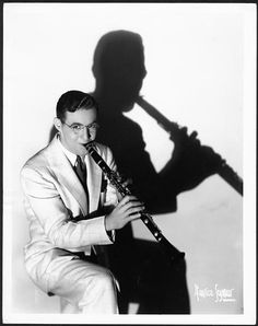 a man in a suit and tie holding a flute with his shadow on the wall behind him