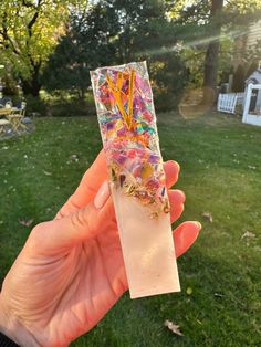 a person holding up a piece of paper in their hand with colorful sprinkles on it