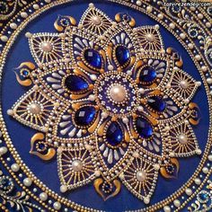 an intricate blue and gold brooch with pearls on it's side, surrounded by other beads