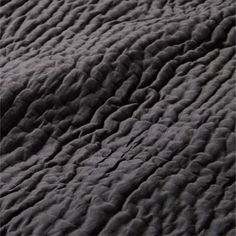 the texture of an unmade bedspread is shown in black and grey tones