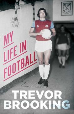 a man standing next to a wall holding a soccer ball