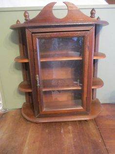 an old wooden display case with glass doors on the top and bottom shelves, sitting on a hard wood floor