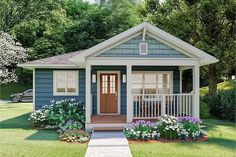 a small blue house with flowers in the front yard