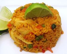 a white plate topped with rice covered in sauce and a lime wedge next to it