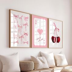 two framed pictures hang on the wall above a bench with white pillows and pink cushions