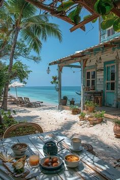 an outdoor table with food on it near the beach and ocean in front of a house