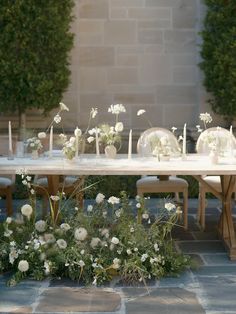 the table is set with white flowers and candles for an outdoor dinner party or reception