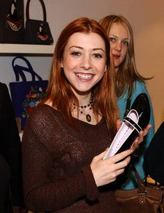 a woman is holding a purse and smiling at the camera