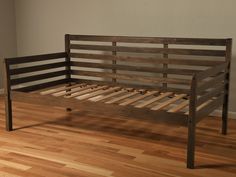 a wooden bed frame sitting on top of a hard wood floor next to a wall