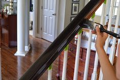 a woman is painting the banisters in her home