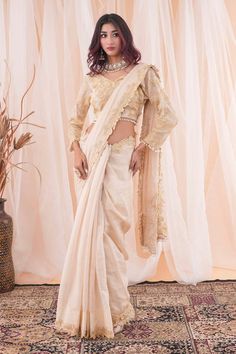 Ivory and beige saree with pearl and cutdana applique work border. Paired with an embroidered blouse with a tasseled hem. - Aza Fashions Elegant Off White Pre-draped Saree For Festive, Traditional Pre-draped Off White Saree With Sheer Dupatta, Off White Pre-draped Saree With Sheer Dupatta, Elegant Saree Blouse Piece With Pearl Embroidery, Elegant Designer Pre-draped Saree With Pearl Embroidery, Elegant Blouse Piece With Pearl Embroidery In Traditional Drape, Silk Pre-draped Saree With Pearl Embroidery For Reception, Raw Silk Blouse For Wedding And Eid, Elegant Beige Traditional Wear With Zari Work