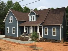 a blue house with white trim and two windows on the front, surrounded by trees