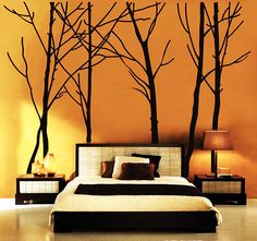 a bedroom with an orange wall and trees painted on the walls, along with a bed