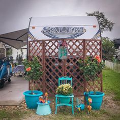 an rv with potted plants in front of it and two chairs next to it