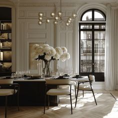 an elegant dining room with white flowers in vases on the table and chairs around it