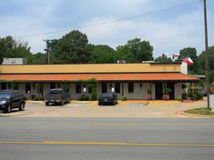 a motel with cars parked in front of it and flags on the top of their roof