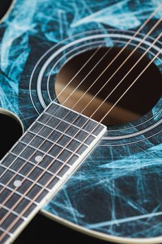 an acoustic guitar with blue swirls on the fret and neck, close up