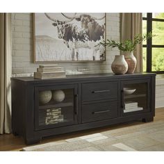 a black entertainment center with two vases on top and a cow painting in the background