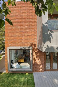 an open window in the side of a brick building next to a wooden deck and green grass