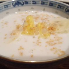 a close up of a bowl of food with cereal and milk in it on a table