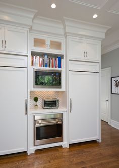 a kitchen with white cabinets and stainless steel oven, microwave and toaster combination in the center