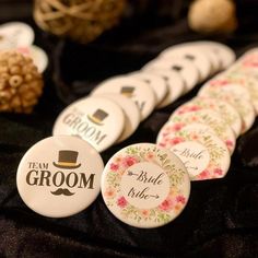 buttons with the words groom and bride on them are sitting on a black tablecloth