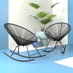 two black rocking chairs sitting next to each other on a blue and white floor near a potted plant