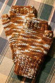 a brown and white knitted mitt sitting on top of a plaid cloth covered floor