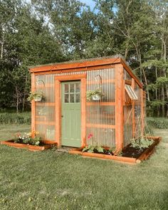 a small garden shed in the middle of some grass