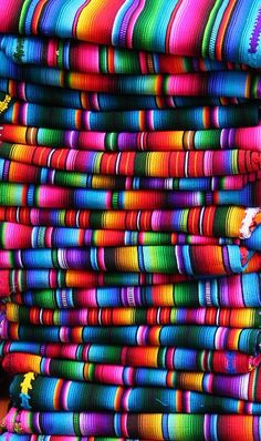 multicolored fabric is stacked on top of each other in the dark, and it looks like they have been made out of yarn