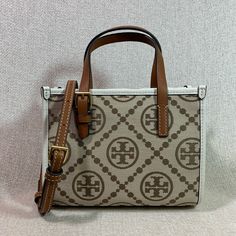 Price Is Firm. In Brand New Never Been Carried Condition. Price Is Firm. In Brand New Never Been Carried Condition. T Monogram Jacquard Mini Tote By Tory Burch. This Bag Is Made Of Genuine Leather Trim And Beige Jacquard With Hazel Logo Dimensions: 7.5” Wide X 6” Tall Center X 3.25" Deep. Handle 3" Drop Long Leather Strap Is Adjustable And Detachable Strap And Handle Are In Tan Leather Snap On Magnetic Button Top Closure Interior: Single Compartment One Slip Card Pocket Beige Microfiber Lining. Beige Monogram Canvas Bag With Monogram Print, White Monogram Canvas Bag For Formal Occasions, Luxury White Bag With Monogram Print, White Monogram Print Bag For Everyday Use, Tan Monogram Bag, Elegant Tan Monogram Bag, Hazel Logo, T Monogram, Button Top