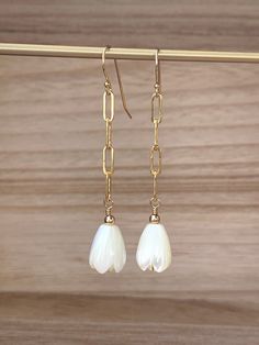 "Delicate mother of pearl hand-carved pikake beads on 14k gold-fill chain. These lightweight earrings measure approximately 2.25\" in total drop length." Delicate White Teardrop Flower Earrings, Handmade White Pearl Earrings In 14k Gold Filled, White Teardrop Jewelry With Flower Charm, White 14k Gold-filled Teardrop Earrings, White Teardrop 14k Gold Filled Earrings, White 14k Gold Filled Teardrop Earrings, Delicate White 14k Gold Filled Earrings, White Teardrop Hypoallergenic Flower Earrings, Handmade White Pearl Earrings 14k Gold Filled