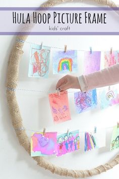 a child's hand hanging pictures on a rope with the words hula hoop picture frame