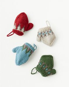 four knitted mittens and gloves sitting on top of a white surface, one is red, the other blue