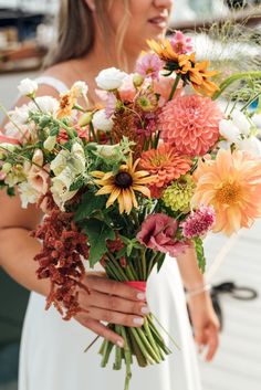 Peach Dahlias, White Doublini Lisianthus, Yellow Rudbeckia Wildflowers Bridal Bouquet, Blush Cosmos, Salmon Rose Benary's Giant Zinnias, Cream and Peach Foxglove, Queen Lime Zinnias, Coral Fountain Amarant, Frosted Explosion Grass.  Large, Lush Wildflower bouquet for a white satin gown for a coastal Maine wedding on the dock.  Asymmetrical, big and lush, rich and fruity, berry colors. Frosted Explosion, Giant Zinnias, August Wedding Flowers, White Satin Gown, Dahlia Bridal Bouquet, Bridal Bouquet Blush, Zinnia Bouquet, White Lisianthus