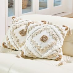 two decorative pillows sitting on top of a white couch