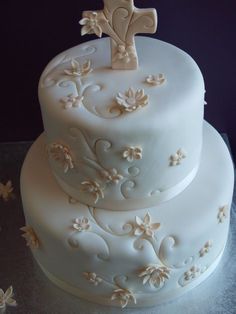 a three tiered cake decorated with flowers and a cross