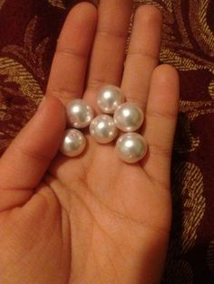 a person holding five pearls in their hand