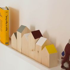 a wooden block with houses on it next to a yellow book and a red stuffed animal