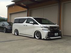 the white van is parked in front of two other cars outside an open garage door