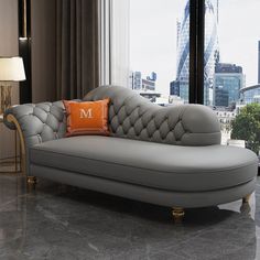 a couch with an orange pillow on it in front of a large window and cityscape