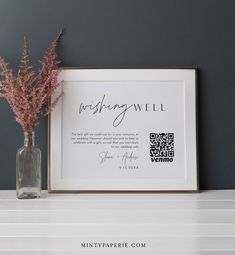 a vase filled with pink flowers sitting next to a framed print on a white shelf