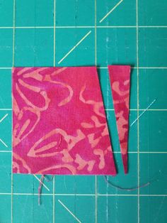 a piece of pink fabric sitting on top of a green cutting board next to scissors