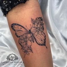 a black and white butterfly with flowers on it's back leg tattoo by adressa mayoara